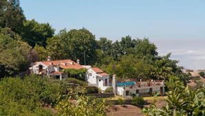 A white villa with a red-tiled roof surrounded by lush greenery and trees. - Finca Casa Nanita B (Moya)