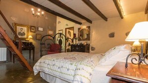 A bedroom with a bed, a wooden headboard, a nightstand, a lamp, and a staircase. - Finca Casa Nanita B (Moya)