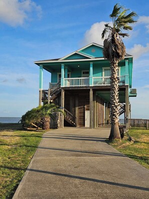 A two-story house with a balcony and a staircase leading to the second floor. - Beautiful Bayfront Retreat with Unbeatable Bay and Gulf Views (Bolivar Peninsula)
