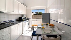 Una cucina con zona pranzo, lavatrice e vista tramite una porta in vetro.