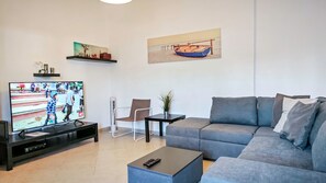 A living room with a TV, sofa, chair, coffee table, and artwork.