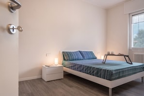 Une chambre à coucher avec un lit, une table de chevet, une lampe et une fenêtre.
