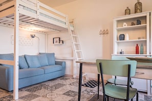 A bunk bed, a desk with a chair, a sofa, and a shelf with decorative items.