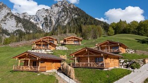 Un rifugio alpino con chalet in legno, ognuno con un balcone e vista sulle montagne circostanti.