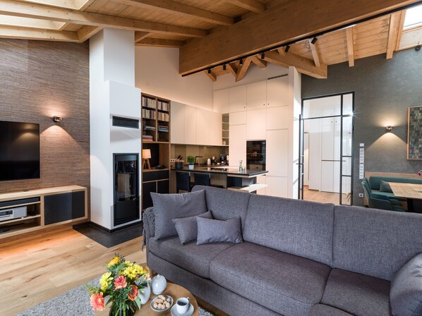 A modern living room with a grey sofa, a flat-screen TV, and a bookshelf.