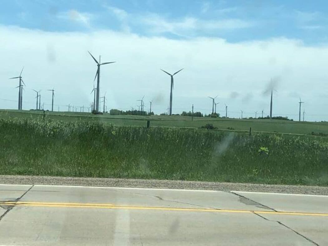 A road with wind turbines in the background.