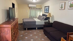 A bedroom with a bed, a TV on a wooden cabinet, a bedside table with a lamp, and a window with curtains. - Cozy and comfy little house in the heart of Loreto (Loreto)