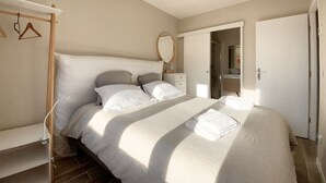A bedroom with a bed, a bedside table, a mirror, and a wardrobe. - Villa Alexandra (Le Crotoy)
