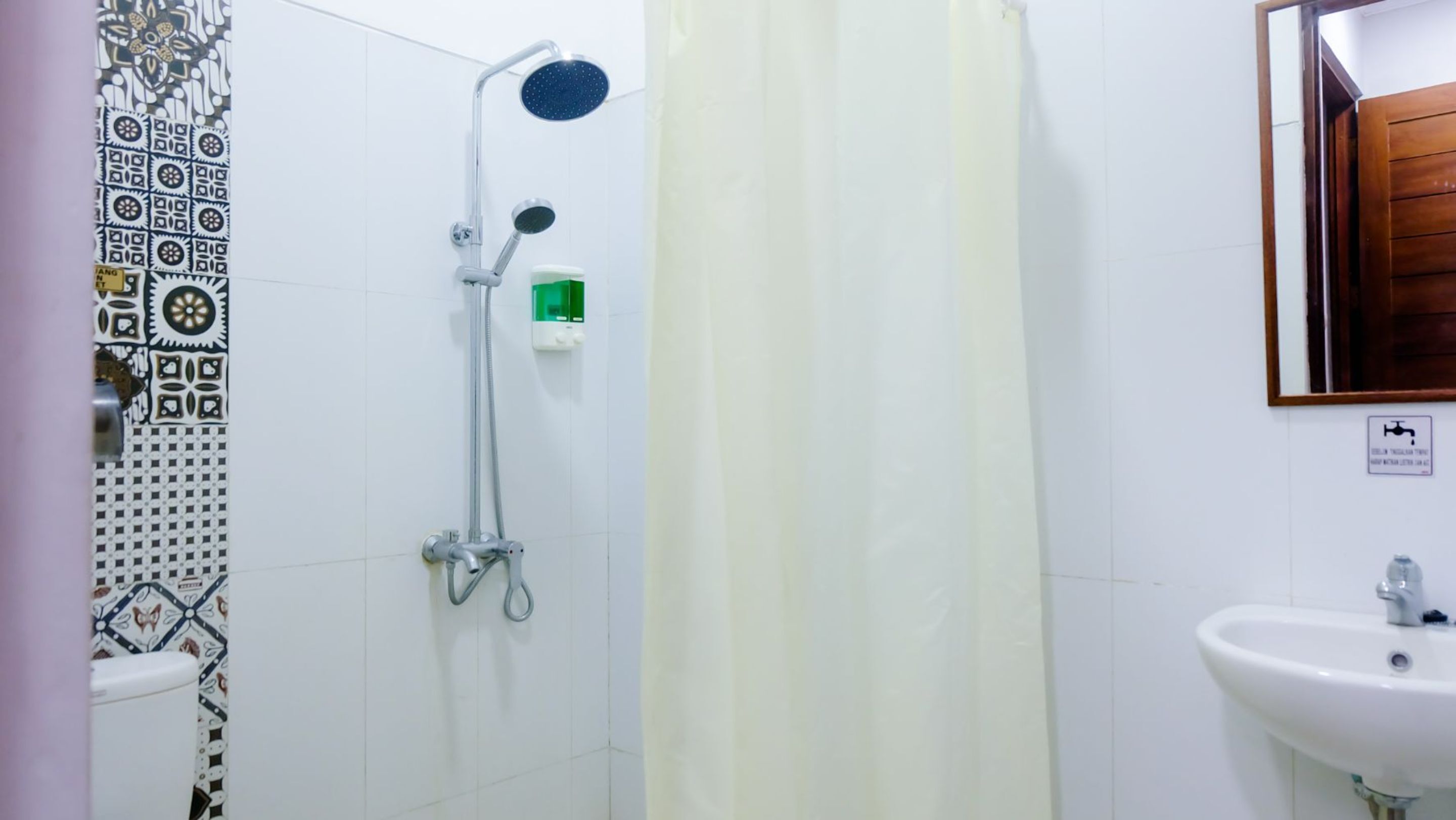 A bathroom with a shower, a sink, and patterned tiles.
