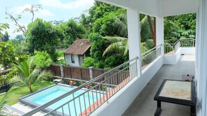 Un balcon donnant sur une piscine et une végétation luxuriante.