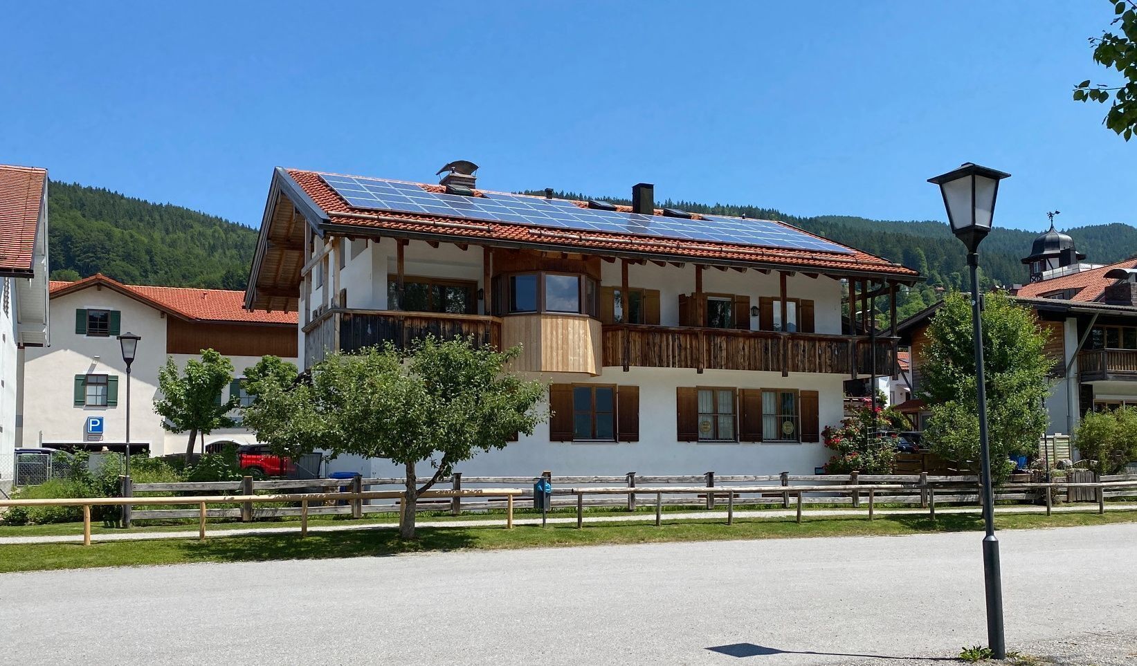 Un edificio a più piani con tetto in tegole rosse, balconi e pannelli solari.
