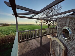A wooden deck with a metal railing overlooking a green field.