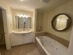 A bathroom with a double vanity, a large bathtub, and a round mirror. - OCEANFRONT! Pool & Land Trans included! (Daufuskie Island)