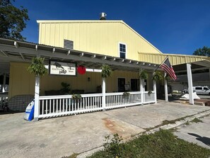A yellow building with a white porch, an American flag, and a sign for Daufuskie Island Liquor Store. - OCEANFRONT! Pool & Land Trans included! (Daufuskie Island)