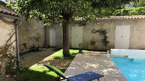 A poolside area with a lounge chair, a small garden, and a tiled patio. - LA Villa Avignon - Centre Ville - Piscine Privée - Intramuros (Avignon)