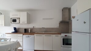 Uma cozinha moderna com armários brancos, micro-ondas embutido, cafeteira, pia e fogão.