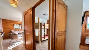 A wooden interior with a bunk bed, a sofa, and a chair. - T3 Apartment in Samoëns Center with Balcony and Private Parking (Samoëns)