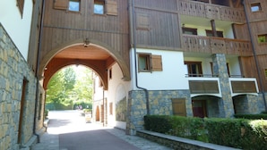 A traditional wooden building with a stone facade, a central archway, and a balcony with wooden railings. - T3 Apartment in Samoëns Center with Balcony and Private Parking (Samoëns)