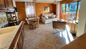 A cozy cabin interior with a kitchen, dining area, and a sofa. - T3 Apartment in Samoëns Center with Balcony and Private Parking (Samoëns)