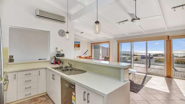 A modern kitchen with a built-in dishwasher, a large window, and a ceiling fan. - Queensland South - Aldinga Beach - C21 SouthCoast Holidays (Aldinga Beach)