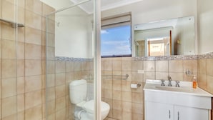 A bathroom with a glass shower enclosure, a toilet, a sink with a mirror, and a window. - Queensland South - Aldinga Beach - C21 SouthCoast Holidays (Aldinga Beach)
