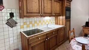 A kitchen with wooden cabinets, a tiled backsplash, and a microwave.