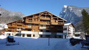 A multi-story wooden building with balconies, surrounded by snow and mountains.