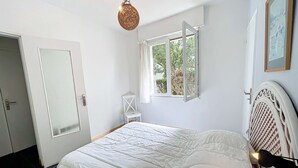 A bedroom with a bed, a window, a chair, and a door.