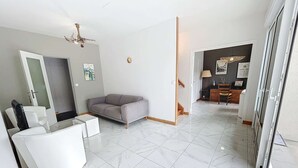 A modern living room with a grey sofa, white furniture, and a tiled floor.