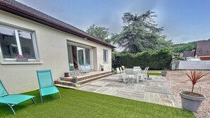 A house with a patio, outdoor seating, and a well-maintained lawn.