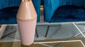 A modern living area with a teal sofa set, a pink vase with dried plants, and a glass coffee table. -  Flamingo Hotel (St. Julian's)