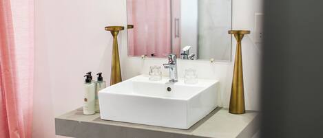 A bathroom with a white sink, two gold-colored candle holders, and a mirror above the sink.