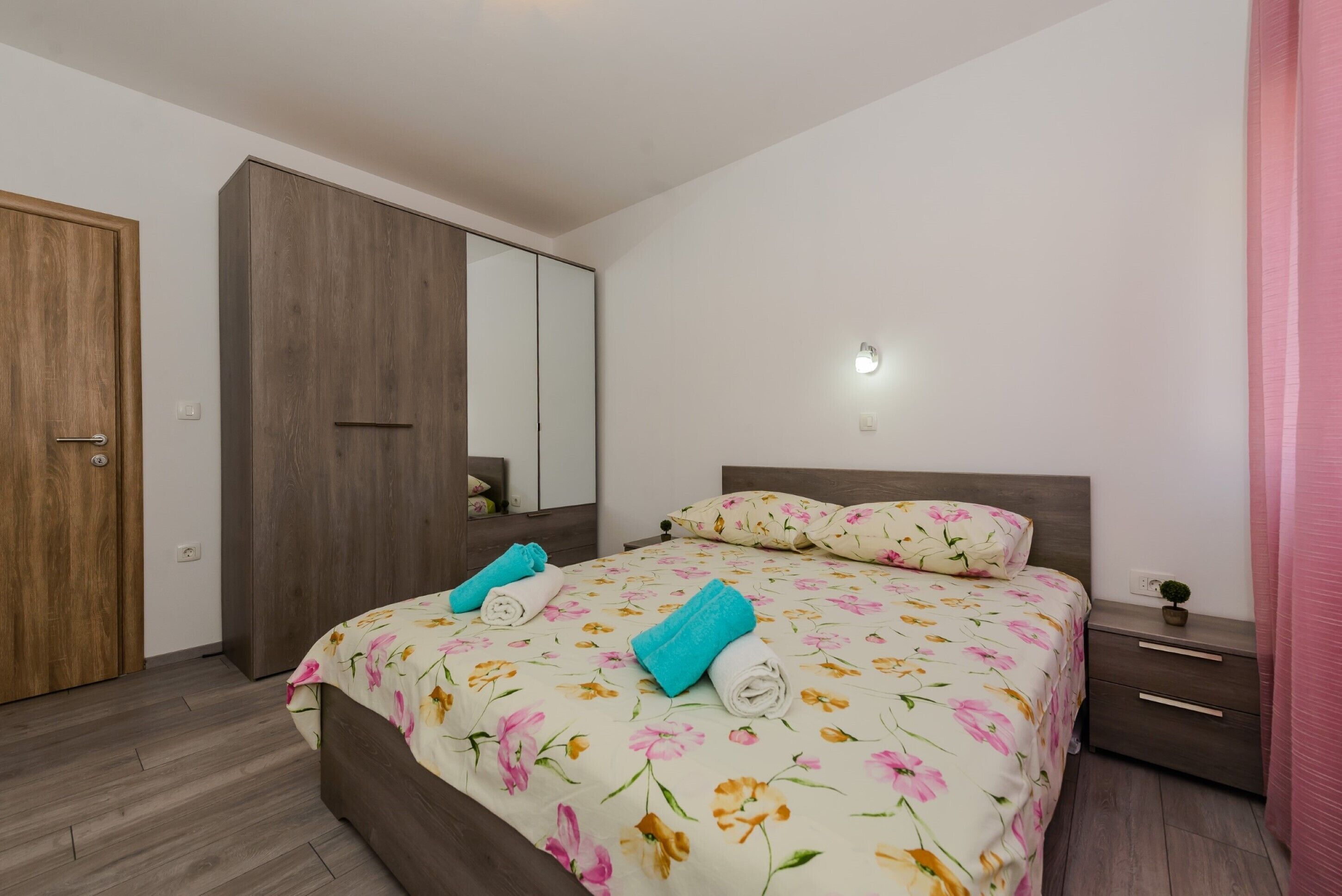Un dormitorio con cama, armario, mesita de noche y espejo.