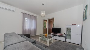 A modern living room with a grey sofa, a glass coffee table, a flat-screen TV, and a white cabinet. - Spacious apt With Lodge Just 40m From the Beach (Kastela)