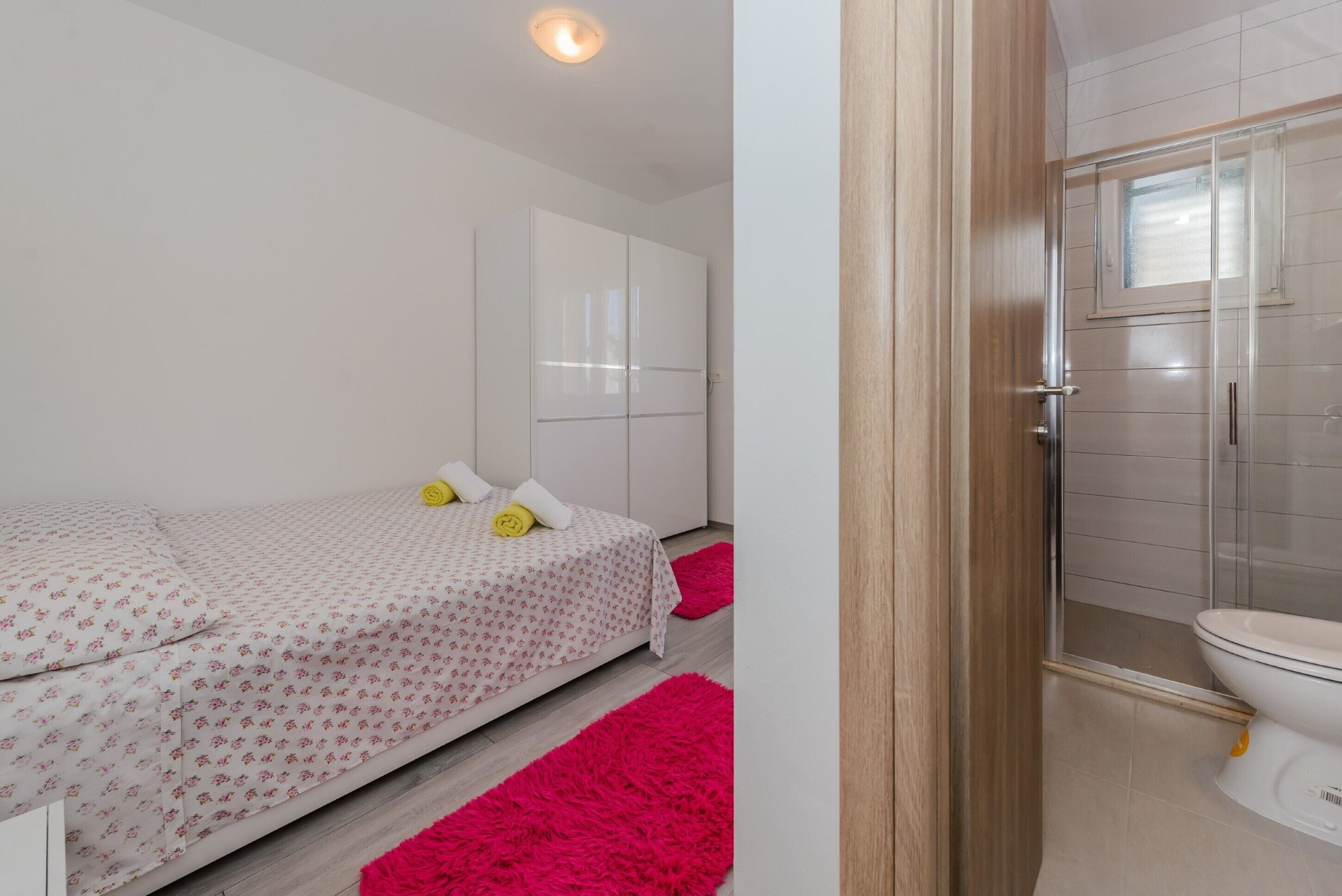 A bedroom with a bed, a wardrobe, and a bathroom with a toilet and shower.