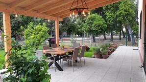 Eine Terrasse im Freien mit einer Holz-Pergola, einem Tisch mit Stühlen und Kübelpflanzen.