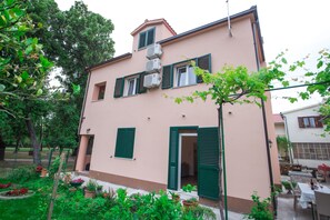A two-story building with green shutters, a small balcony, and a garden area with potted plants. - Spacious Apartment w Patio 40m From the Beach (Kastela)
