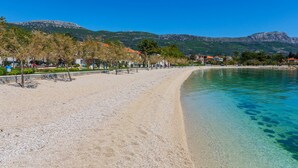 A beach with clear water, a sandy shore, and a mountain in the background. - Seafront Spacious Apt, 120 m2 Size, in the Center (Kastela)