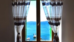 A window with striped curtains, a view of the sea, and a boat in the distance. - Seafront Spacious Apt, 120 m2 Size, in the Center (Kastela)