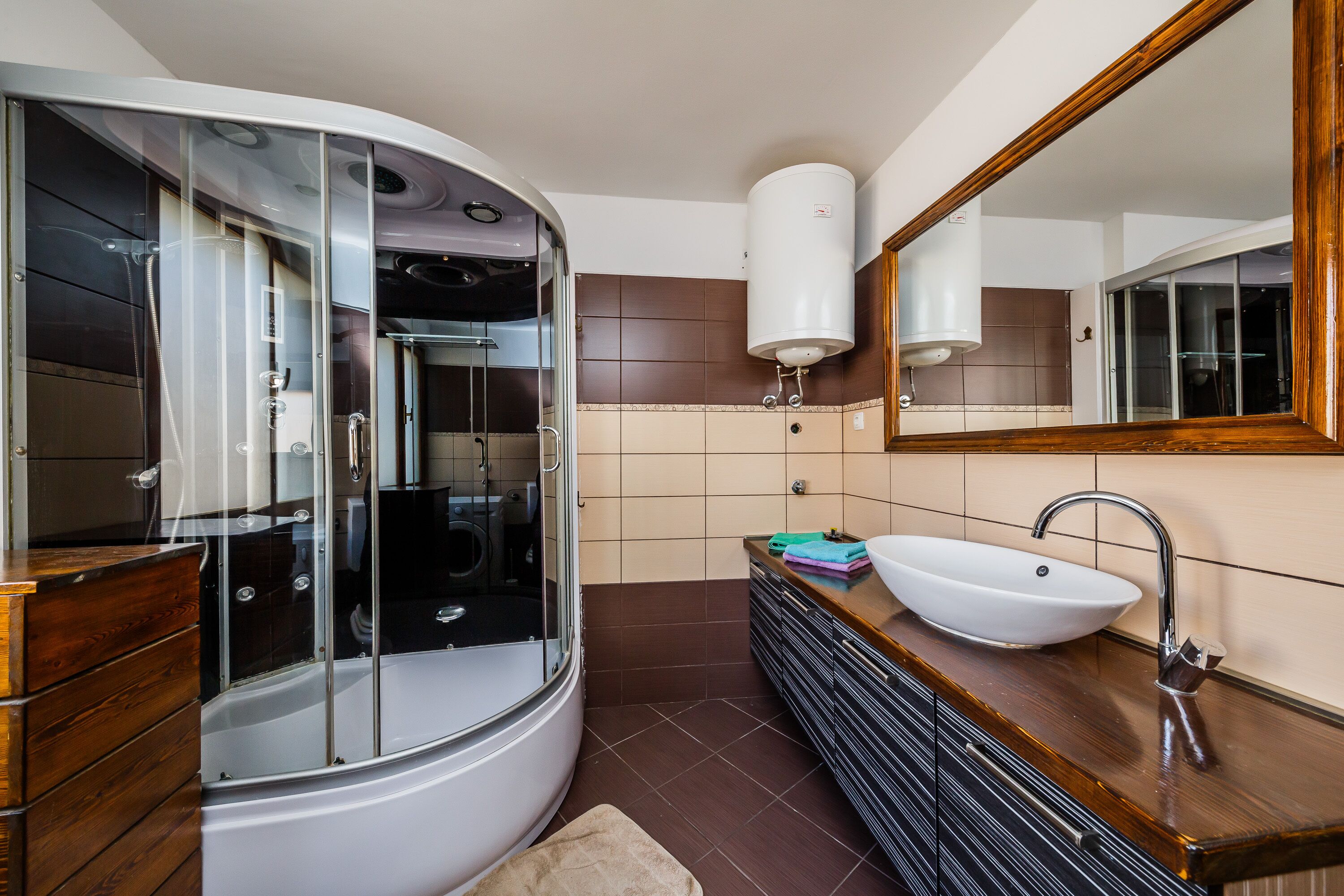 A modern bathroom with a glass-enclosed shower, a white sink, and a large mirror.