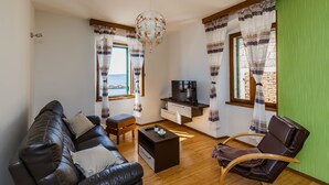 A living room with a leather sofa, a wooden coffee table, a TV stand, and a chair. - Seafront Spacious Apt, 120 m2 Size, in the Center (Kastela)