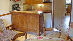 Una cucina compatta con mobili in legno, un forno a microonde, una macchina per il caffè e un lavello.