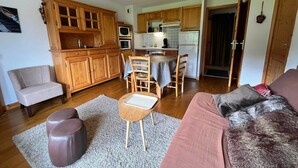 A compact living space with a kitchenette, a dining area, and a seating area with a sofa and ottoman.