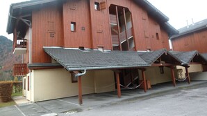 A wooden chalet with a balcony, a staircase, and a covered outdoor seating area.