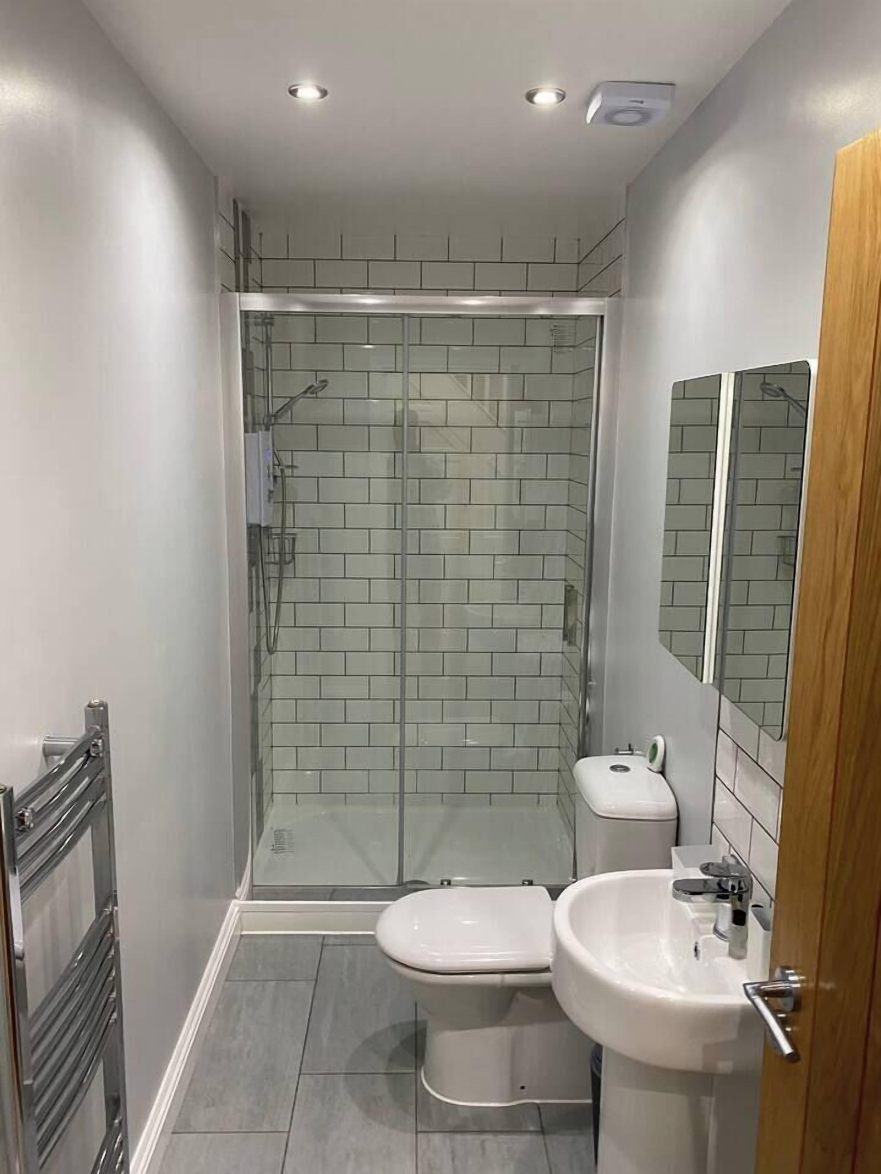 A modern bathroom with a glass-enclosed shower, a toilet, and a sink.