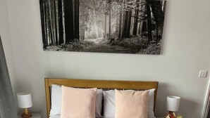 Cama bem arrumada com um cobertor rosa, duas toalhas dobradas e um prato de croissants na cama.