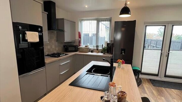Cozinha moderna com ilha central, eletrodomésticos de aço inoxidável e uma grande janela que permite entrada de luz natural.