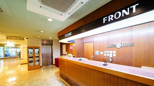 A reception desk with a 'CLOAK' sign, a 'Smile Hotel' logo, and a 'FRONT' sign above. - Smile Hotel Nabar (Nabari)