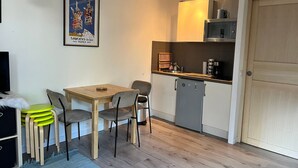 A compact kitchen with a dining area, featuring a small refrigerator, a coffee machine, and a microwave.