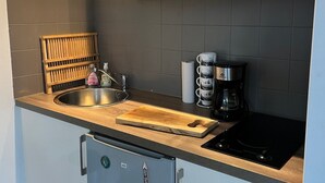 A kitchen with a stainless steel sink, wooden cutting board, coffee maker, and a microwave above the counter.